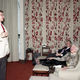 Tom Clancy speaking in the White House screening room while First Lady Barbara Bush laughs and President Bush looks on (February 19, 1990, George Bush Presidential Library and Museum)